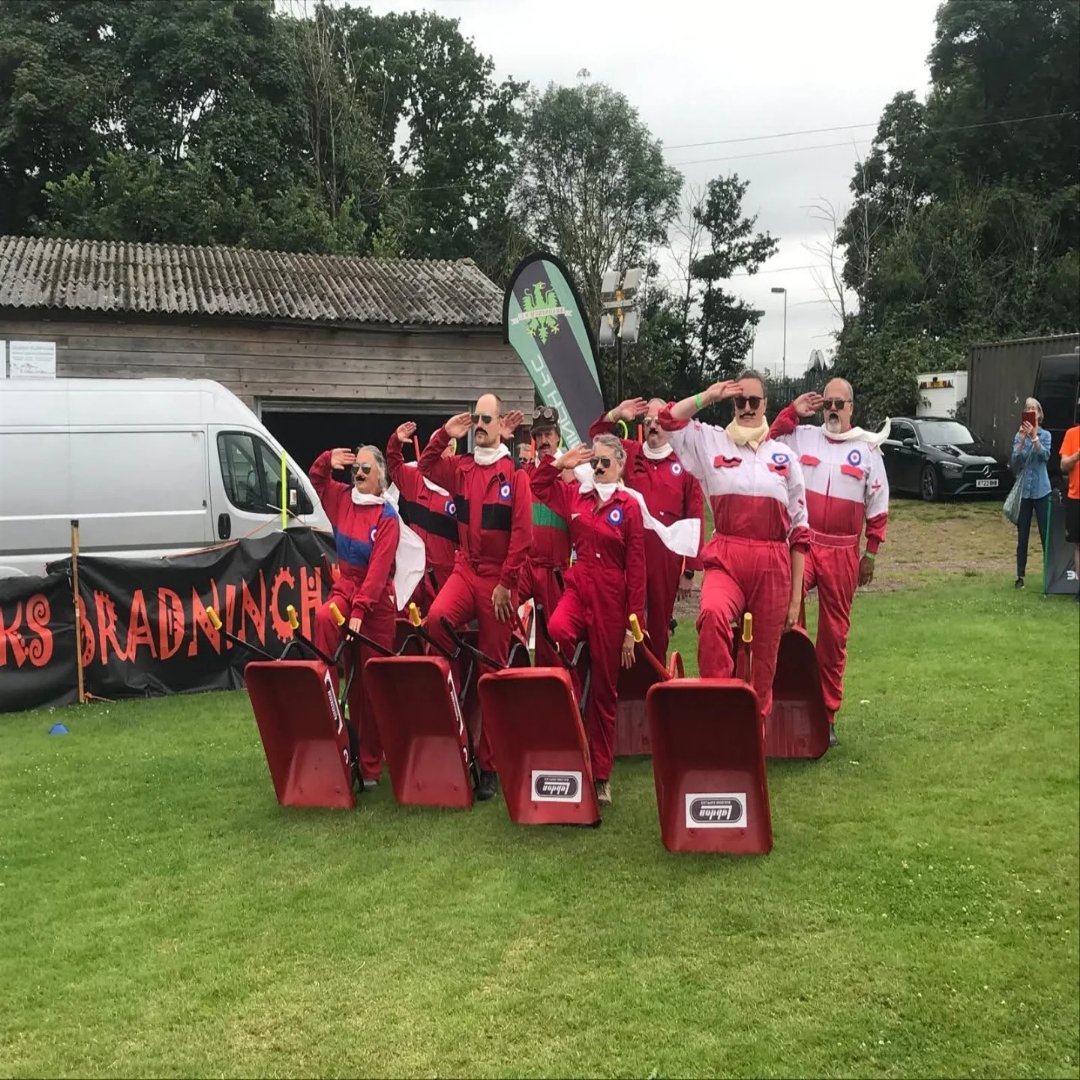 Team saluting with tilted wheelbarrows at Bradninch
